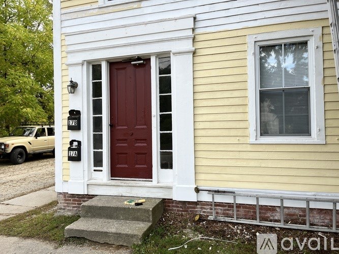 A yellow house with a red door and a white window.