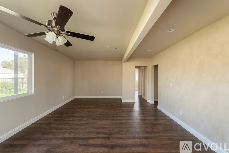 A spacious room with a ceiling fan and hardwood flooring.