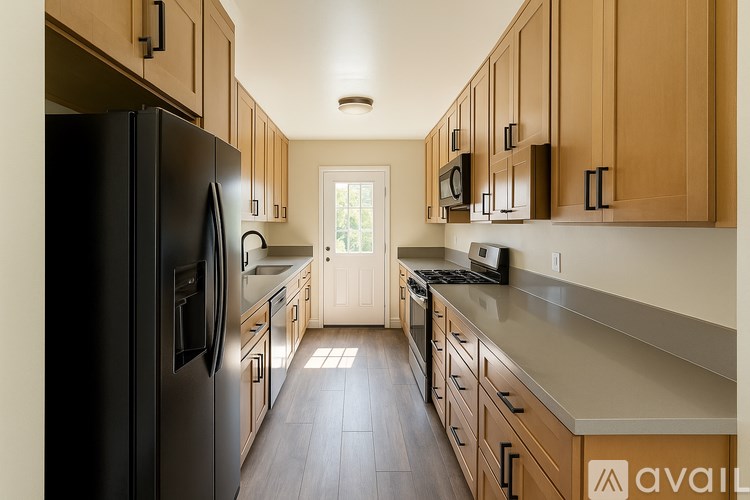 A kitchen with wooden cabinets and a black refrigerator.