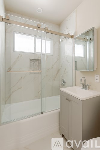 A bathroom with a marble wall and a glass shower.