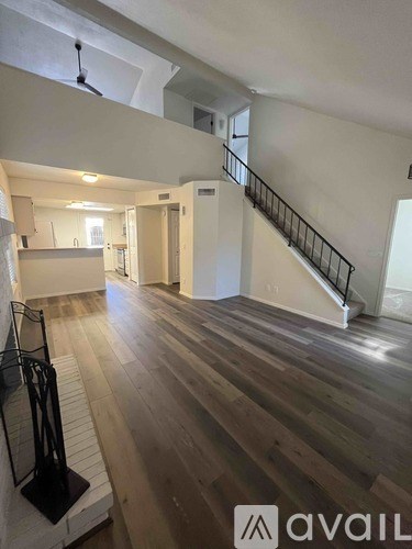 A spacious room with wooden floors and a staircase with a metal railing.