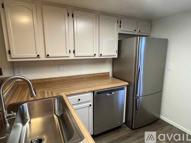 A kitchen with a sink, refrigerator, and cabinets.