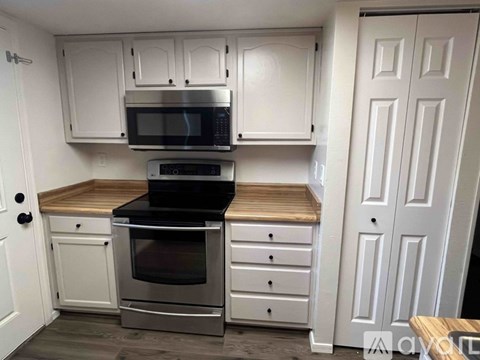 A kitchen with white cabinets and a microwave above the stove.