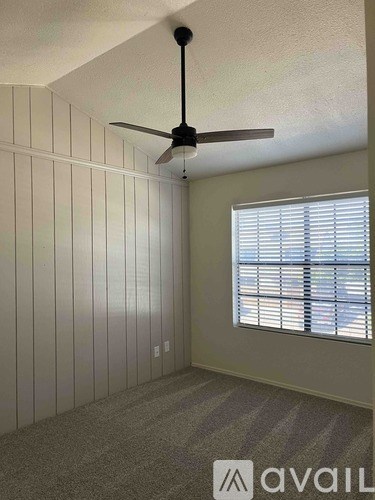 A room with a ceiling fan and a window with blinds.
