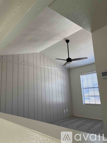 A room with a ceiling fan and a window with blinds.