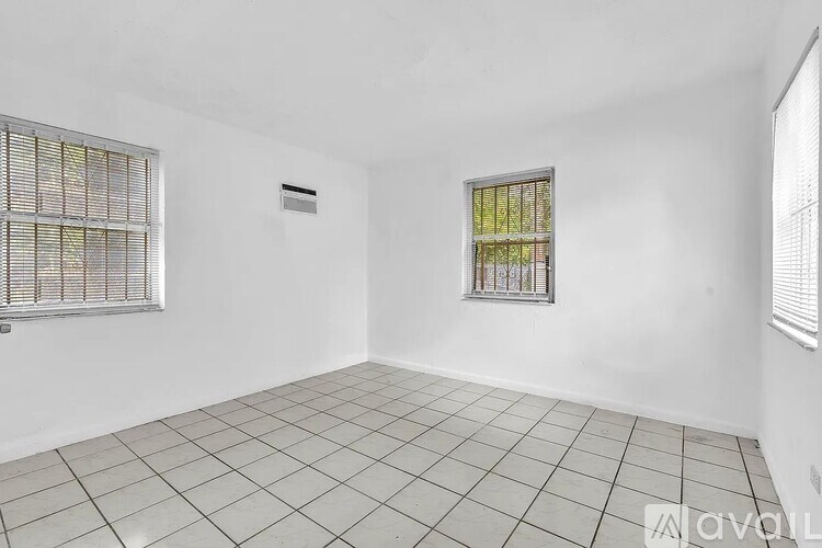 A room with white walls, a window with bars, and a tiled floor.
