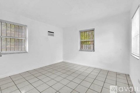 A room with white walls, a window with bars, and a tiled floor.
