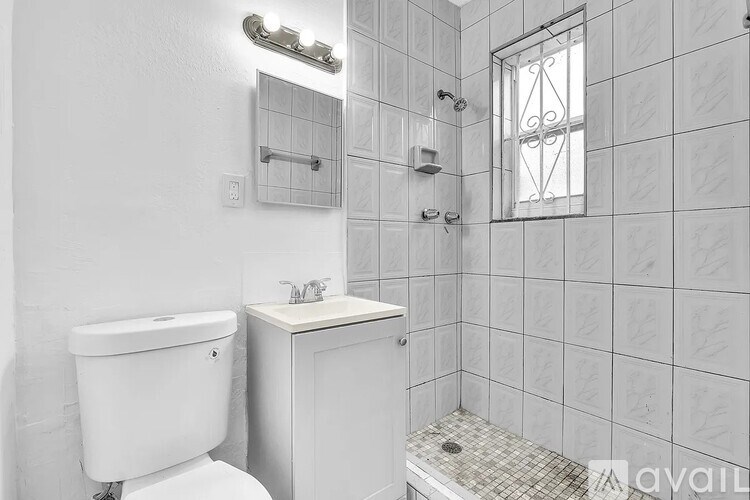 A white bathroom with a toilet, sink, and shower.
