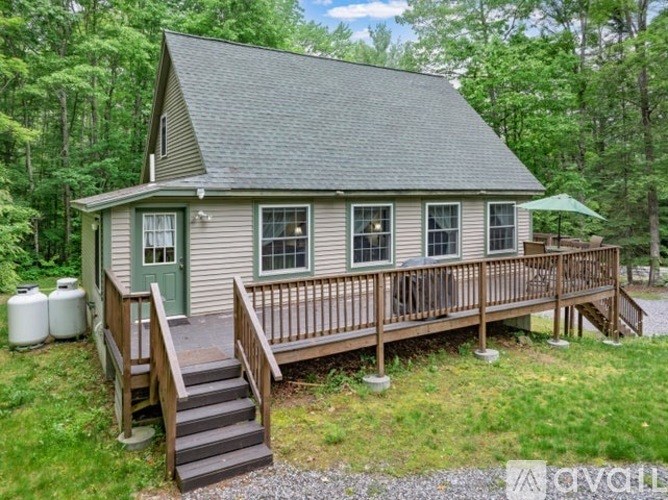 A small house with a green door and a wooden deck.