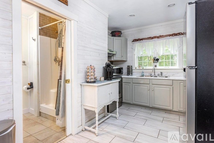 A kitchen with white cabinets and a black refrigerator.