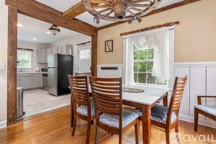 A kitchen with a table and chairs in the foreground and a refrigerator in the background.