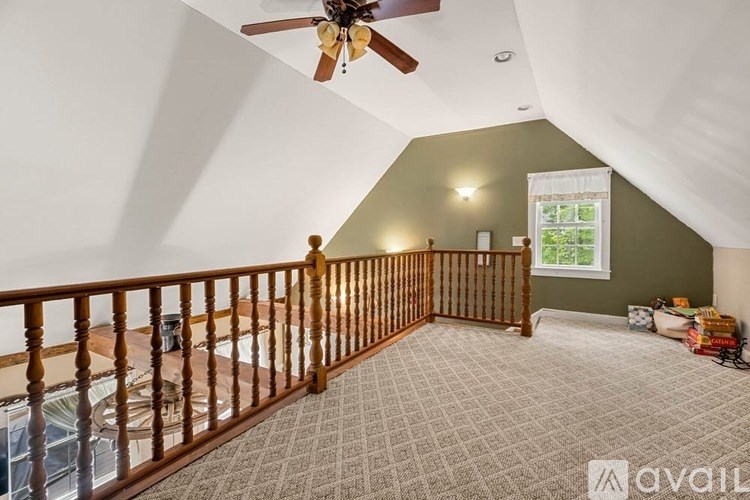 A room with a ceiling fan and a window with a view of trees.