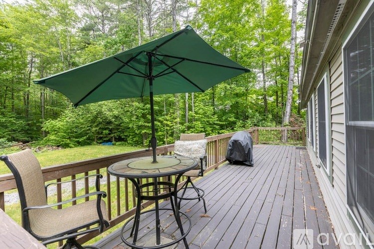 A small table with two chairs and an umbrella on a wooden deck.