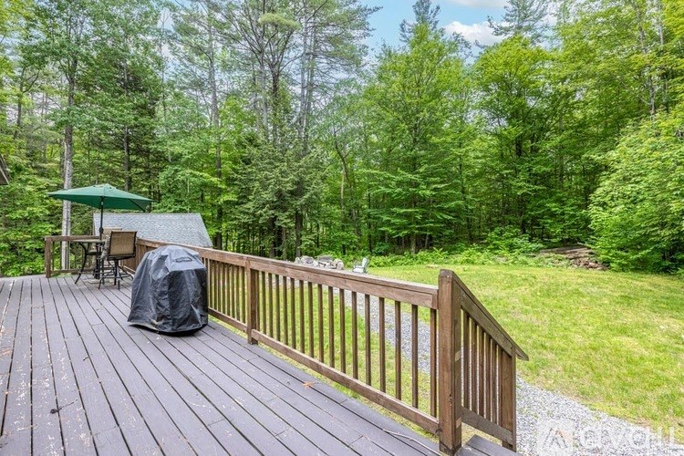 A wooden deck with a black tarp and a green umbrella.