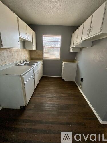 A kitchen with white cabinets and a wooden floor.
