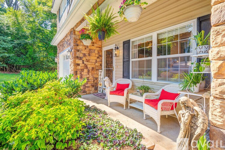 A house with a red chair and a white bench on the porch.