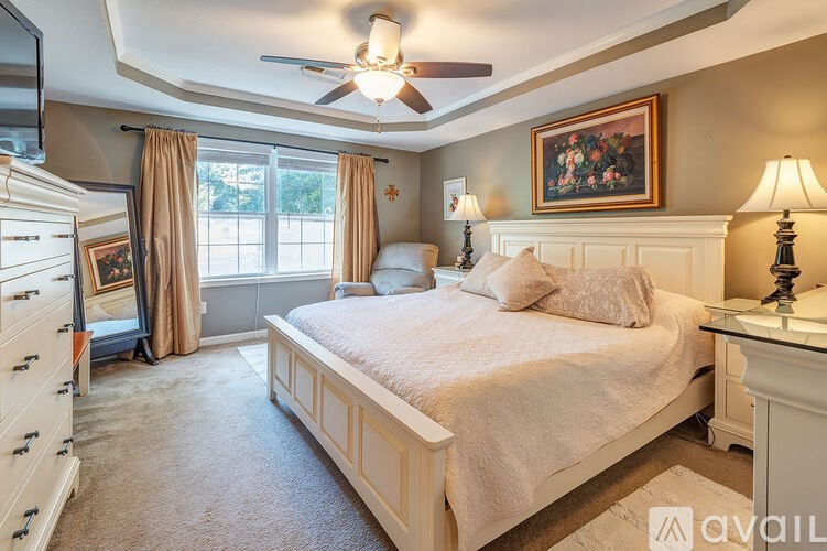 A bedroom with a large bed, a dresser, and a ceiling fan.