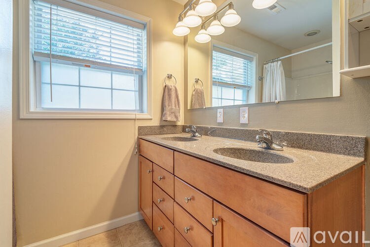 A bathroom with a sink, mirror, and a window with blinds.