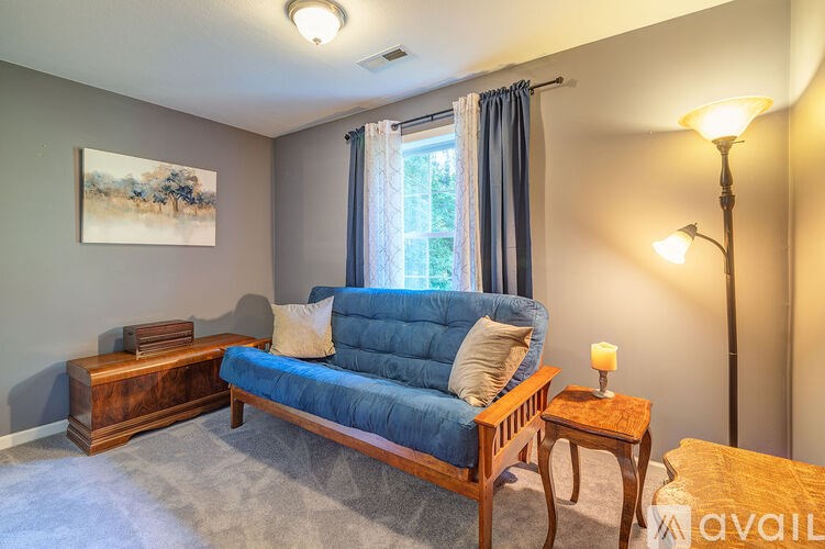 A blue couch sits in a living room with a wooden table and lamp.