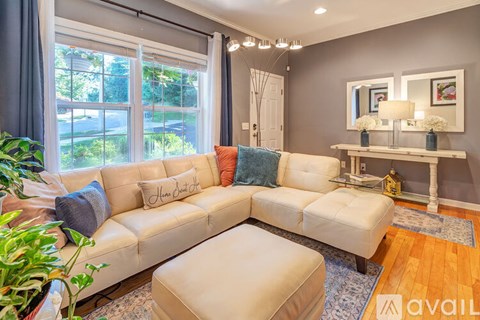 A living room with a large sectional sofa and a small ottoman in front of it.