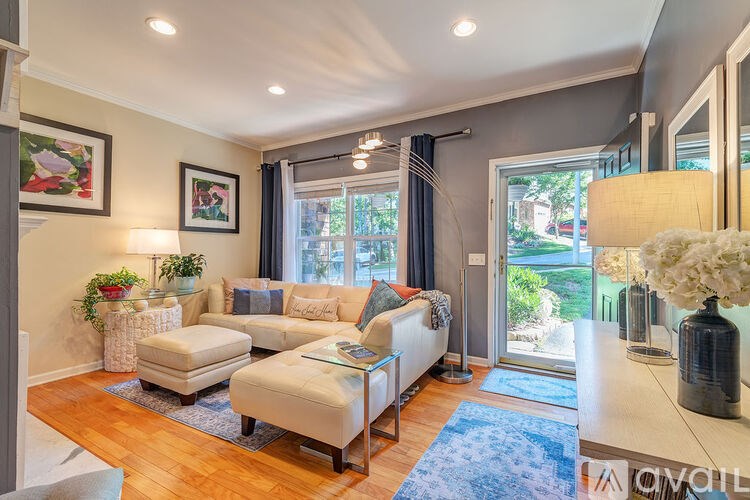 A well-lit living room with a white sofa and a wooden floor.