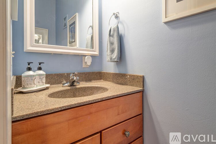 A bathroom with a sink, mirror, and a towel hanging on the wall.