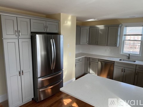 A kitchen with a stainless steel refrigerator and cabinets.