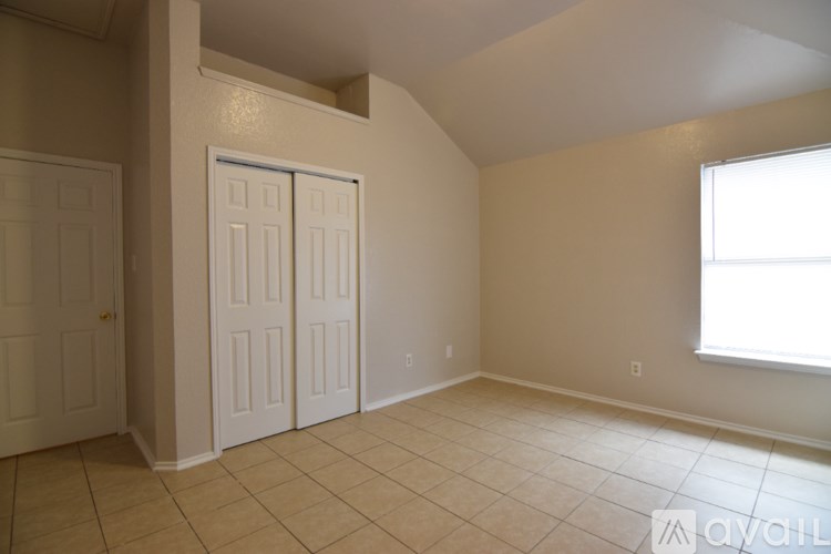 A room with a tan floor and walls, a window, and a door.