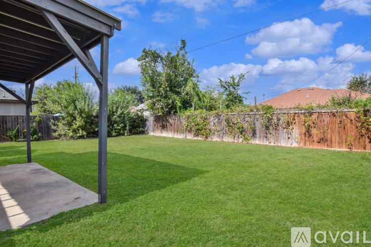 A backyard with a wooden fence and a covered patio area.