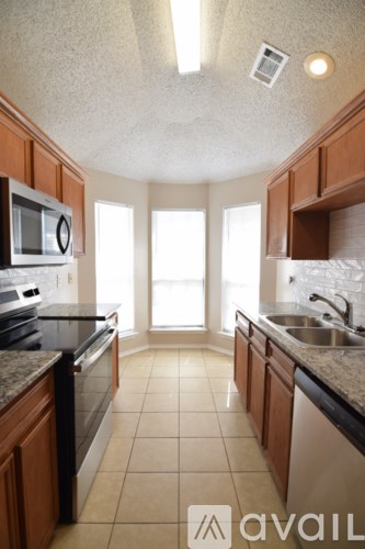 A kitchen with brown cabinets and black countertops.