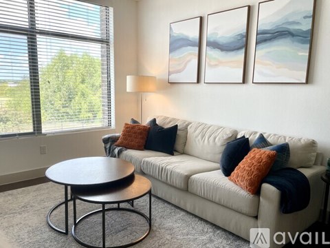 A living room with a couch, a table, and three paintings on the wall.