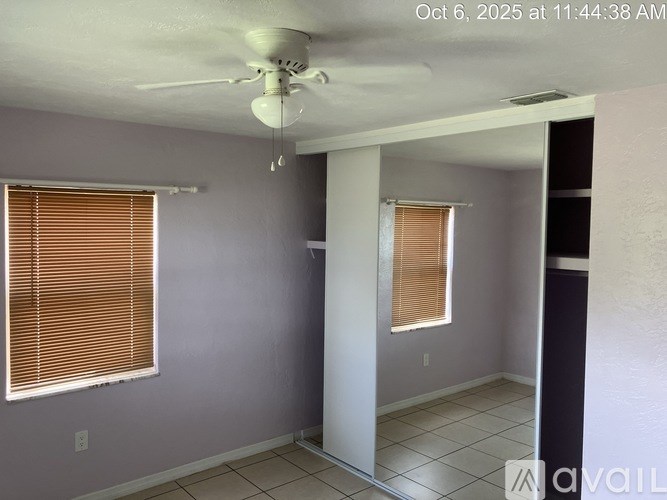 A room with a ceiling fan and a window with blinds.