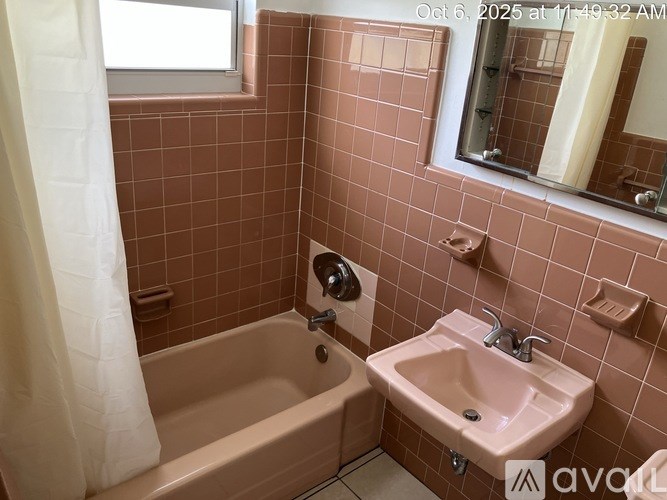 A bathroom with a pink tile wall and a white shower curtain.