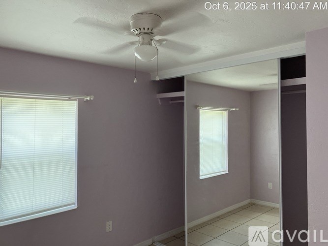 A room with a ceiling fan and a window with blinds.
