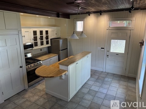 A kitchen with white cabinets and a wooden island.