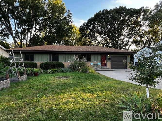 A house with a brown roof and a green lawn in front.