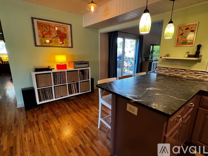 A kitchen with a black counter top and wooden floors.