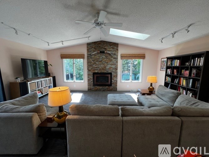 A living room with a grey couch, a fireplace, and a ceiling fan.