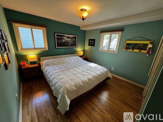 A bedroom with a white bed and wooden floors.