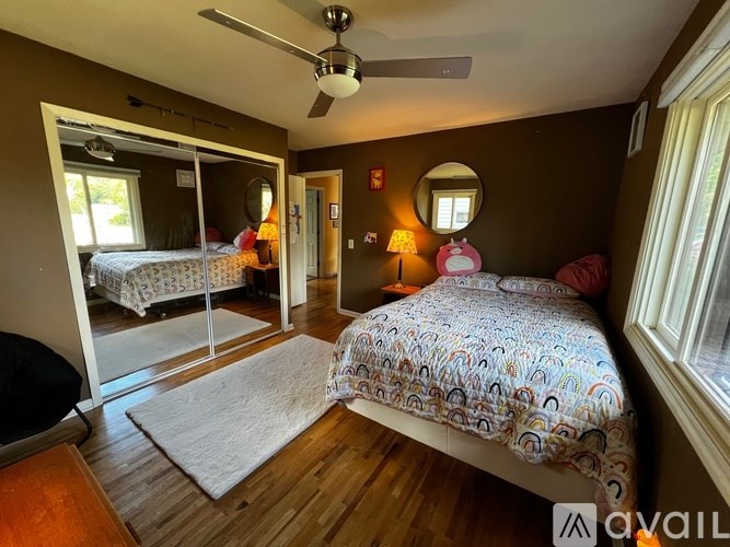 A bedroom with a bed, a ceiling fan, and a mirror.
