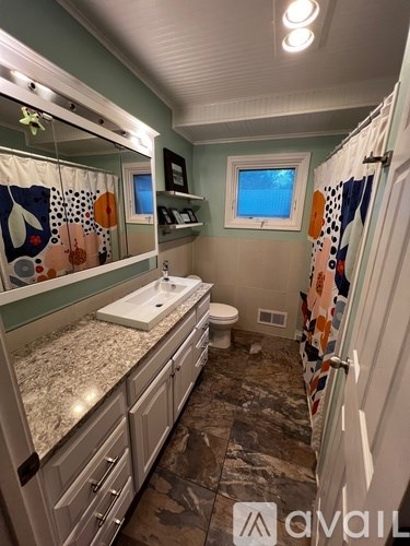 A bathroom with a sink, toilet, and a window.