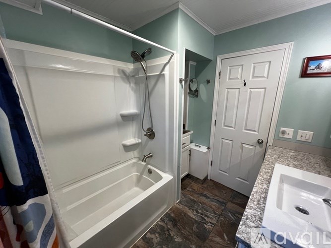 A white bathtub with a shower head and a white door in a bathroom.