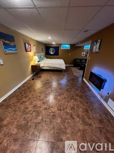 A room with brown flooring and a bed in the middle.