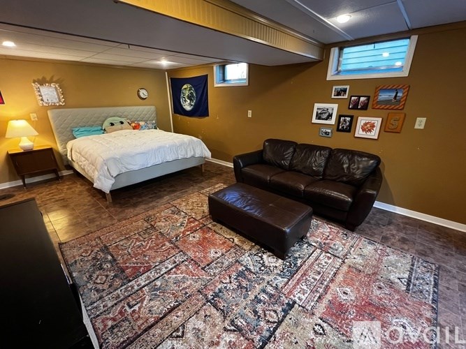 A bedroom with a bed, couch, and rug.
