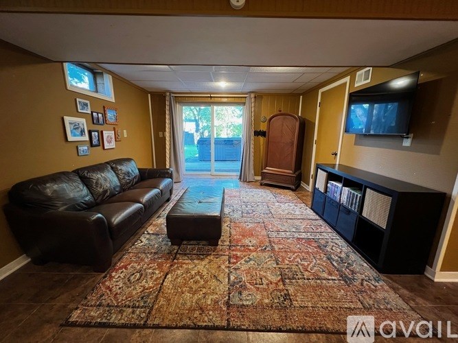 A living room with a brown leather couch and a rug.