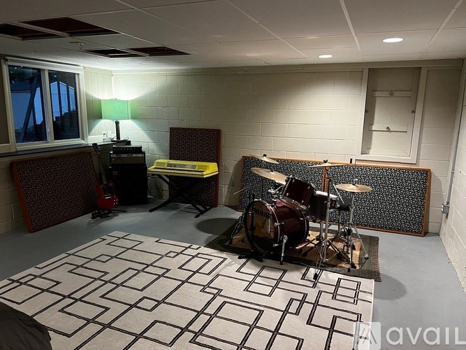 A room with a drum set and a keyboard on a stand.