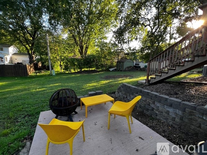 A patio with a yellow chair and table set with a grill.