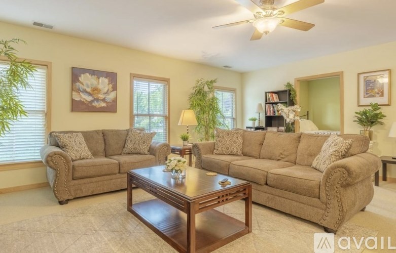 A living room with a brown sofa, a coffee table, and a ceiling fan.