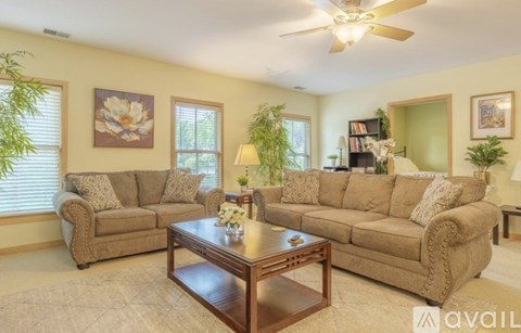 A living room with a brown sofa, a coffee table, and a ceiling fan.