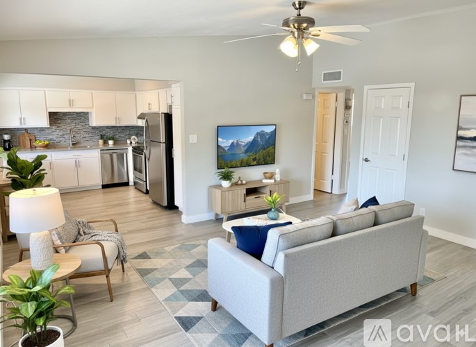 A living room with a grey couch and a television on the wall.
